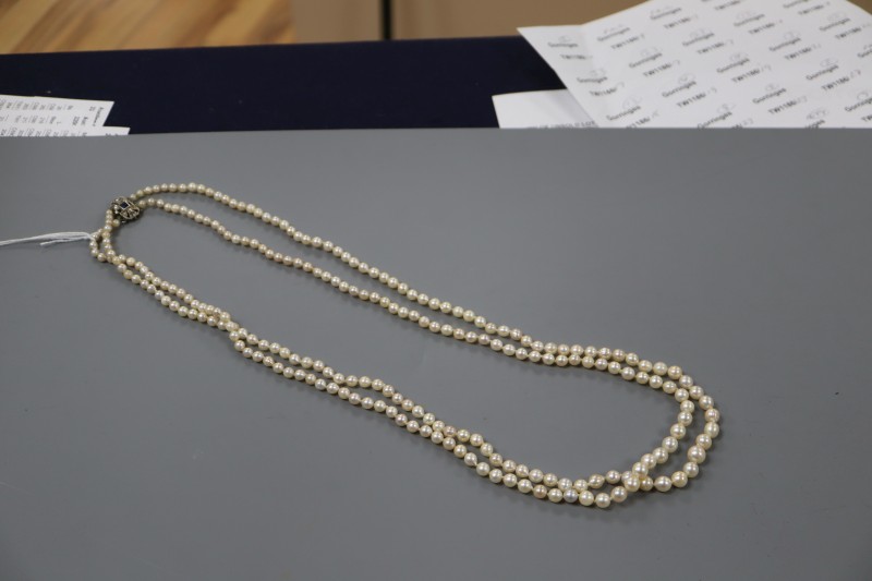 A double strand graduated cultured pearl necklace, with sapphire and diamond set white metal clasp, 70cm.